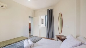 Ein Hotelzimmer mit Bett, Nachttisch, Spiegel und einem Fenster mit Vorhängen.