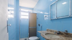 Ein Badezimmer mit blauen Fliesen, einer Toilette, einem Waschbecken und einer Dusche.