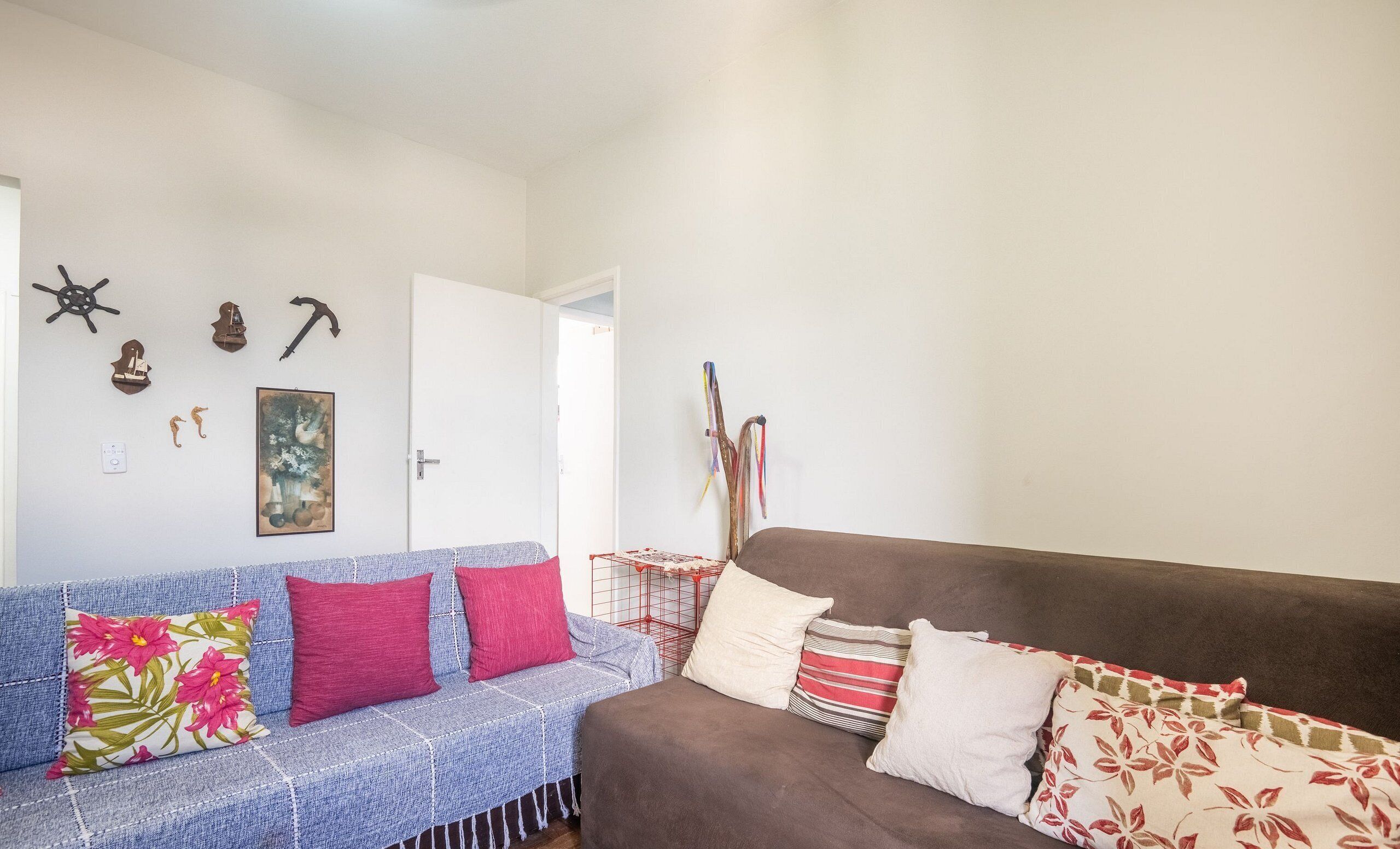 Ein Wohnzimmer mit einem blauen und einem braunen Sofa, beide mit verschiedenen Kissen. An den Wänden sind Dekorationen wie ein Schiffsschwester, ein Gem älde und eine Vogelkäfig zu sehen.