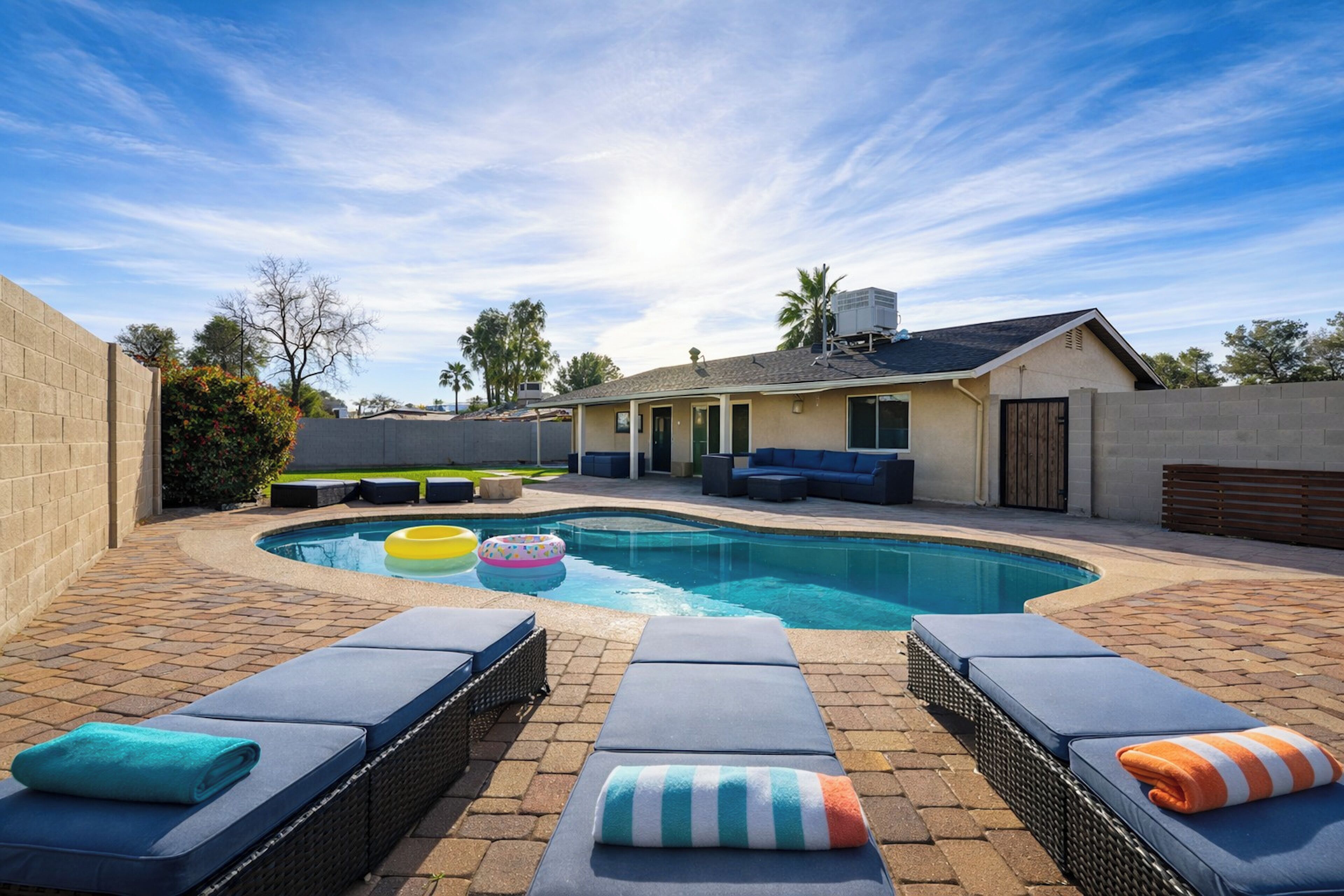 Un jardin avec une piscine, des chaises longues et un espace patio.