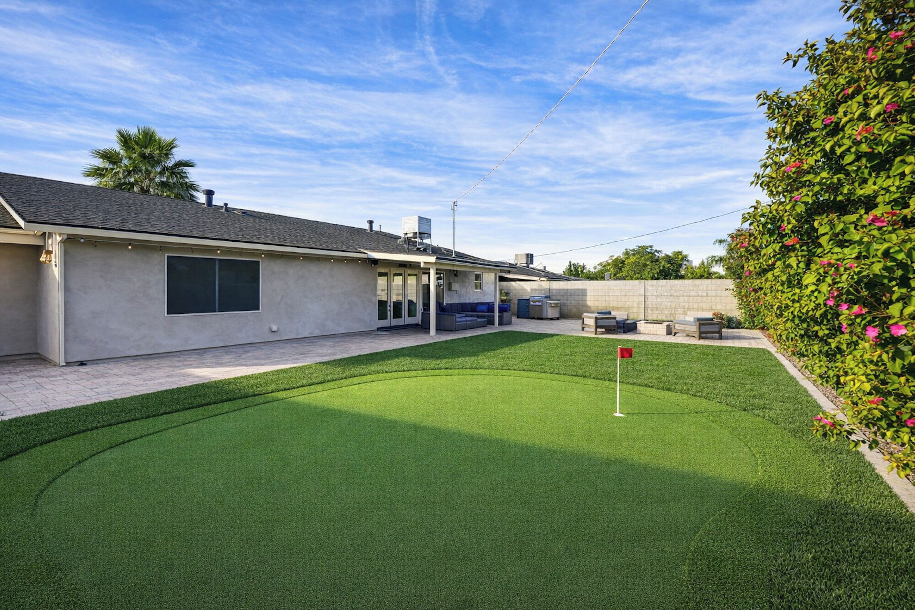 Una proprietà residenziale con un prato ben curato, una zona patio con mobili da esterno e una casa dal design moderno.