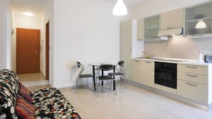 A compact kitchen with a dining area, a sofa, and a patterned rug. - Enjoy a stylish 1-bedroom apartment in the heart of Sliema, just steps from the promenade, beaches, cafés, and bus stops. Fully equipped with Wi-Fi, air conditioning, and kitchen — ideal for couples or small families visiting Malta. (Tas-Sliema)