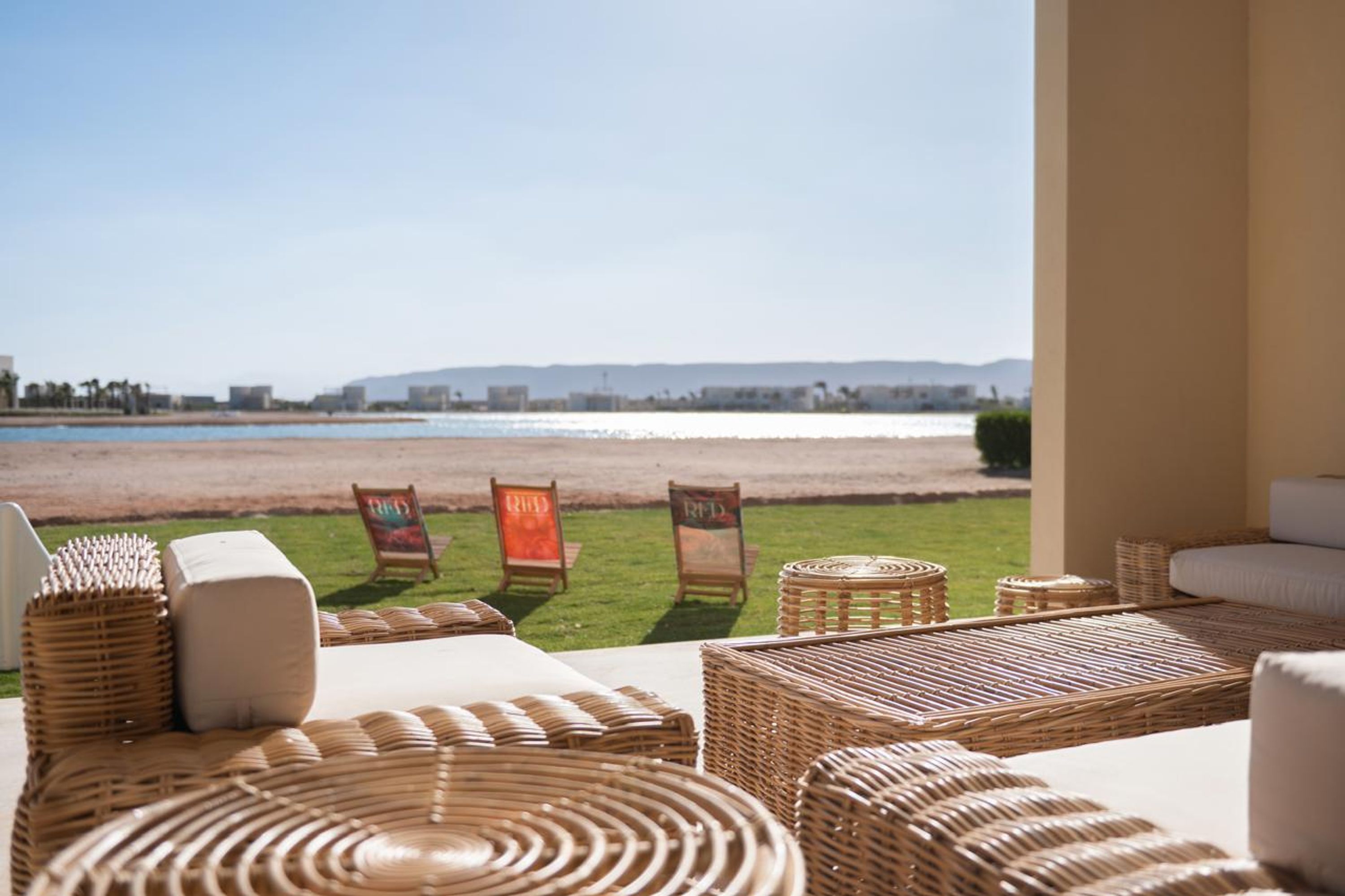 Un espacio de relax junto a la playa con mobiliario de mimbre y vista al mar.
