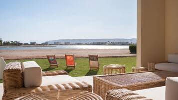 Un espacio de relax junto a la playa con mobiliario de mimbre y vista al mar.