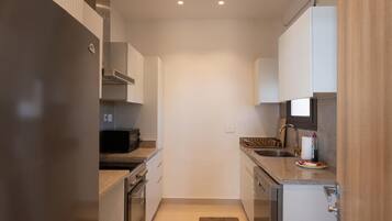 Una cocina compacta con electrodomésticos de acero inoxidable, microondas y lavaplatos.