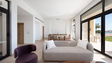 Una sala moderna con un sofá, una mesa de centro y un comedor con una mesa y sillas.