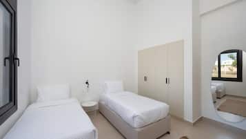 Un dormitorio minimalista con dos camas, un armario, una mesita redonda y una ventana con vistas.