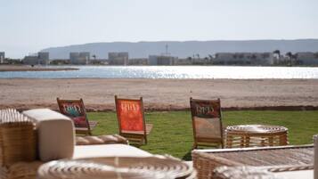 A beachside seating area with wicker furniture and chairs labeled "RED" and "BLUE".