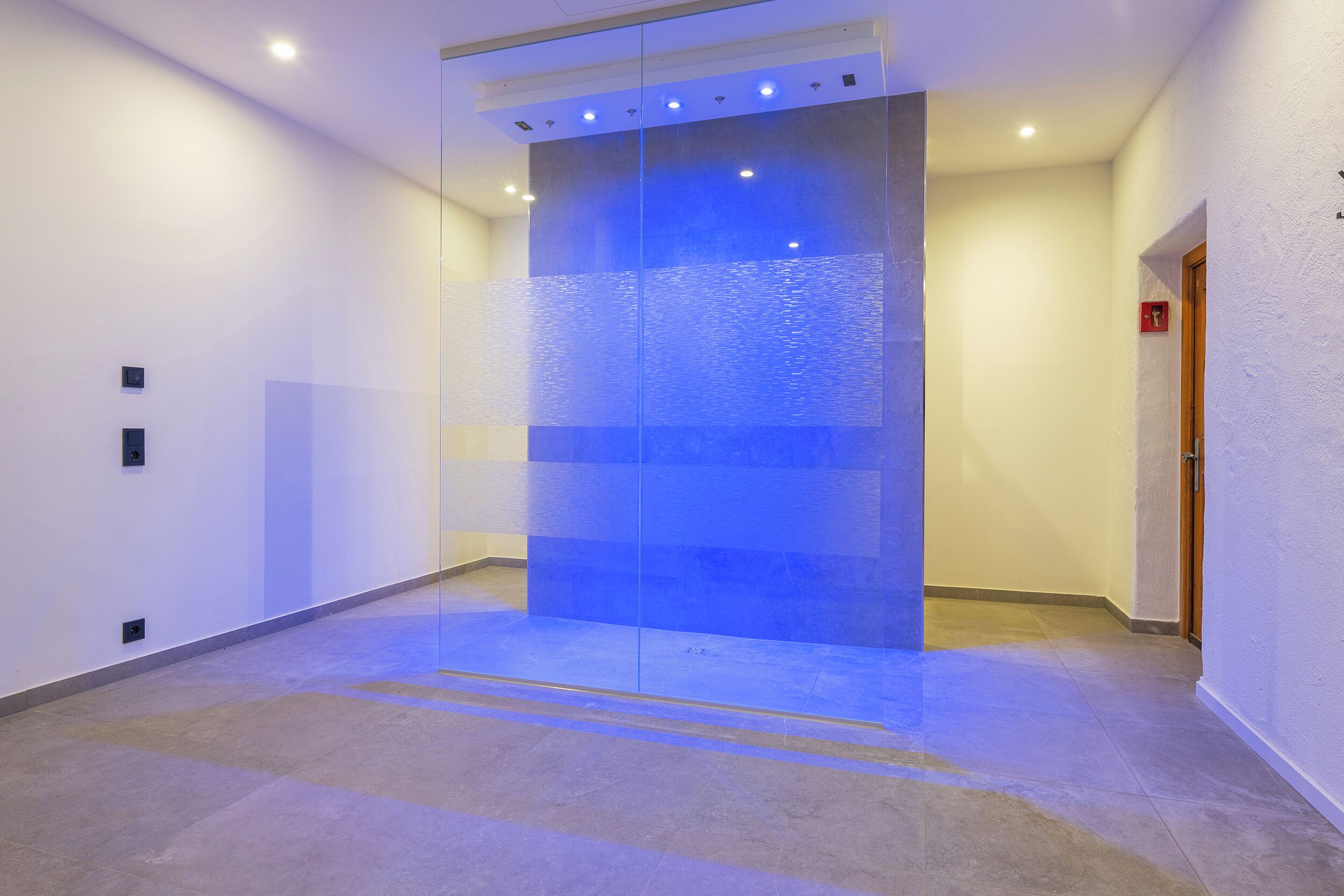 A hallway with a glass partition and recessed lighting.