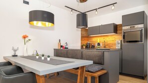 A modern kitchen with a central island, built-in appliances, and pendant lighting. - MyWinkl-Design-Ferienwohnungen  (Reit im Winkl)