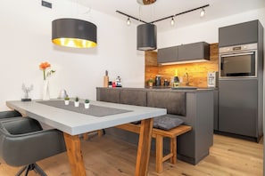A modern kitchen with a central island, built-in appliances, and pendant lighting. - MyWinkl-Design-Ferienwohnungen  (Reit im Winkl)