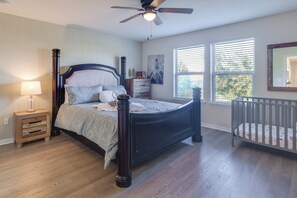 A bedroom with a dark wooden bed, a nightstand, a crib, and a ceiling fan. - Heated Pool & Theater: Solterra 5BR Home Near WDW (Davenport)