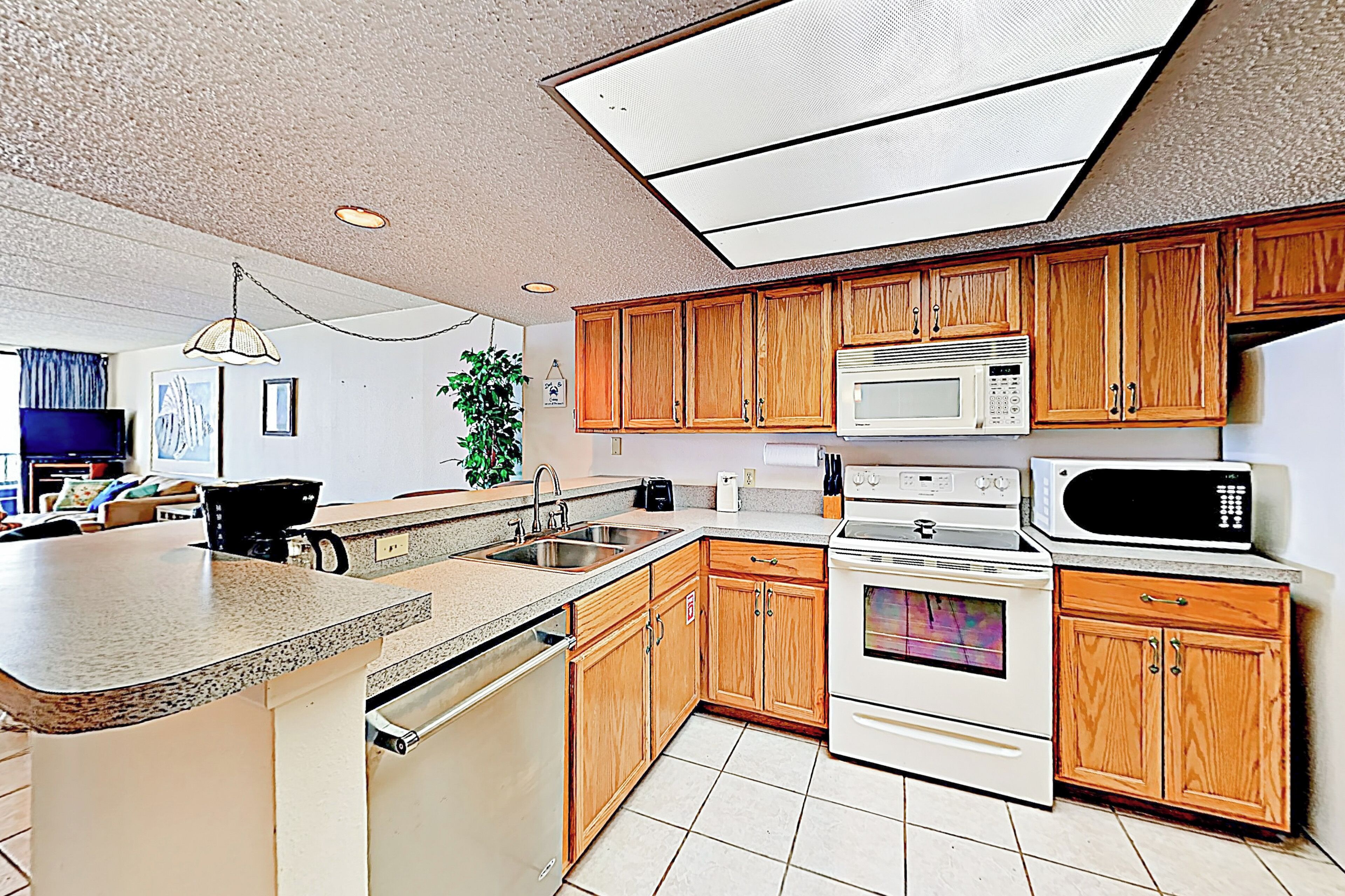 A kitchen with wooden cabinets, a microwave, an oven, a sink, and a countertop.