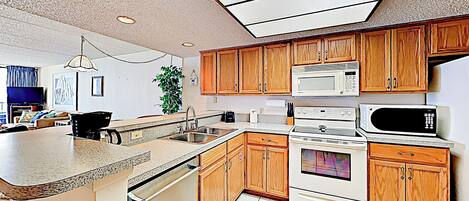 A kitchen with wooden cabinets, a microwave, an oven, a sink, and a countertop.