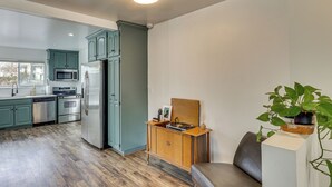 A modern kitchen with teal cabinets, stainless steel appliances, and a wooden cabinet with a record player. - 3 Mi to Geha Field at Arrowhead: Easy Match Access (Independence)