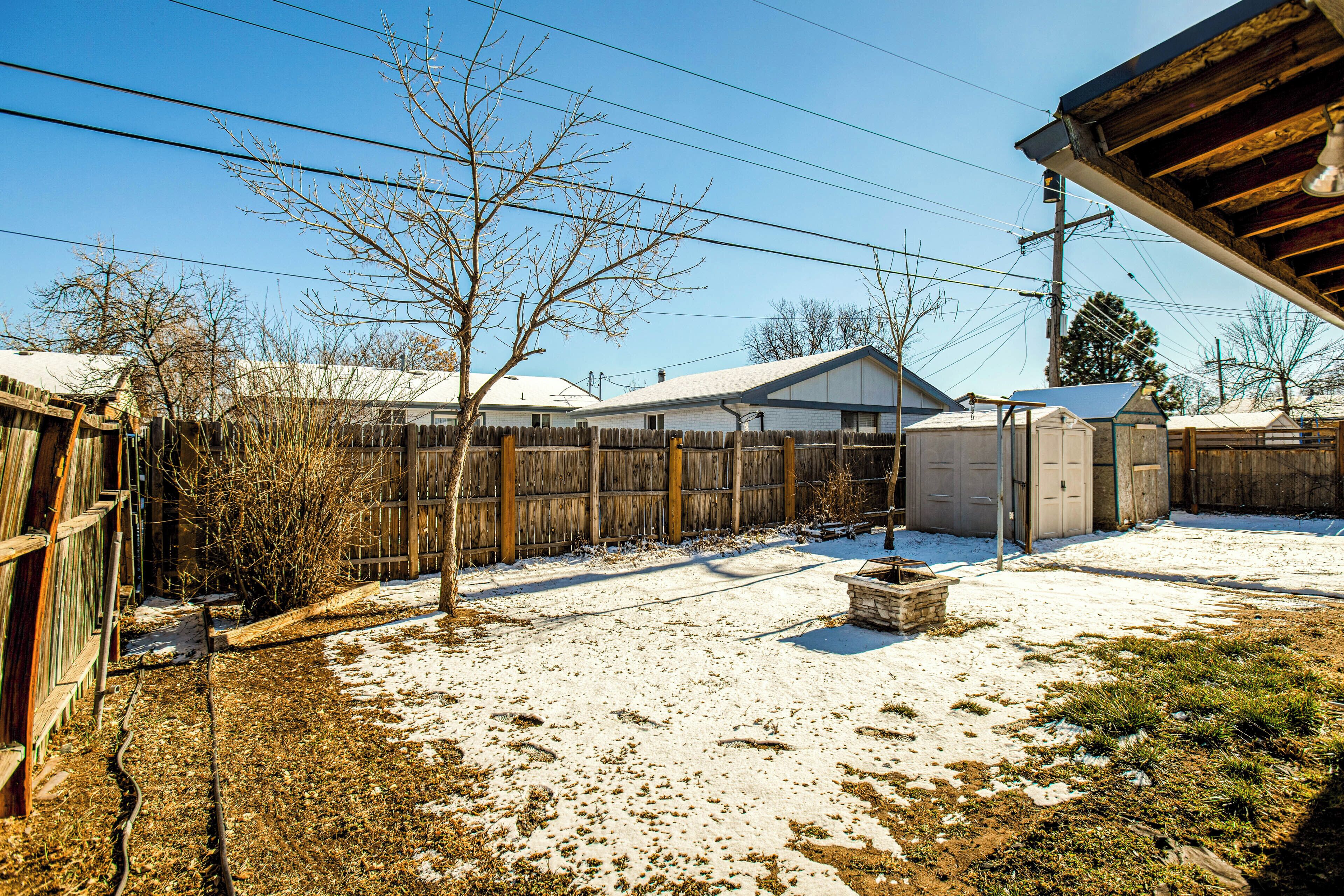 Ein Garten mit Holzzaun, Gartenhaus und schneebedecktem Boden.