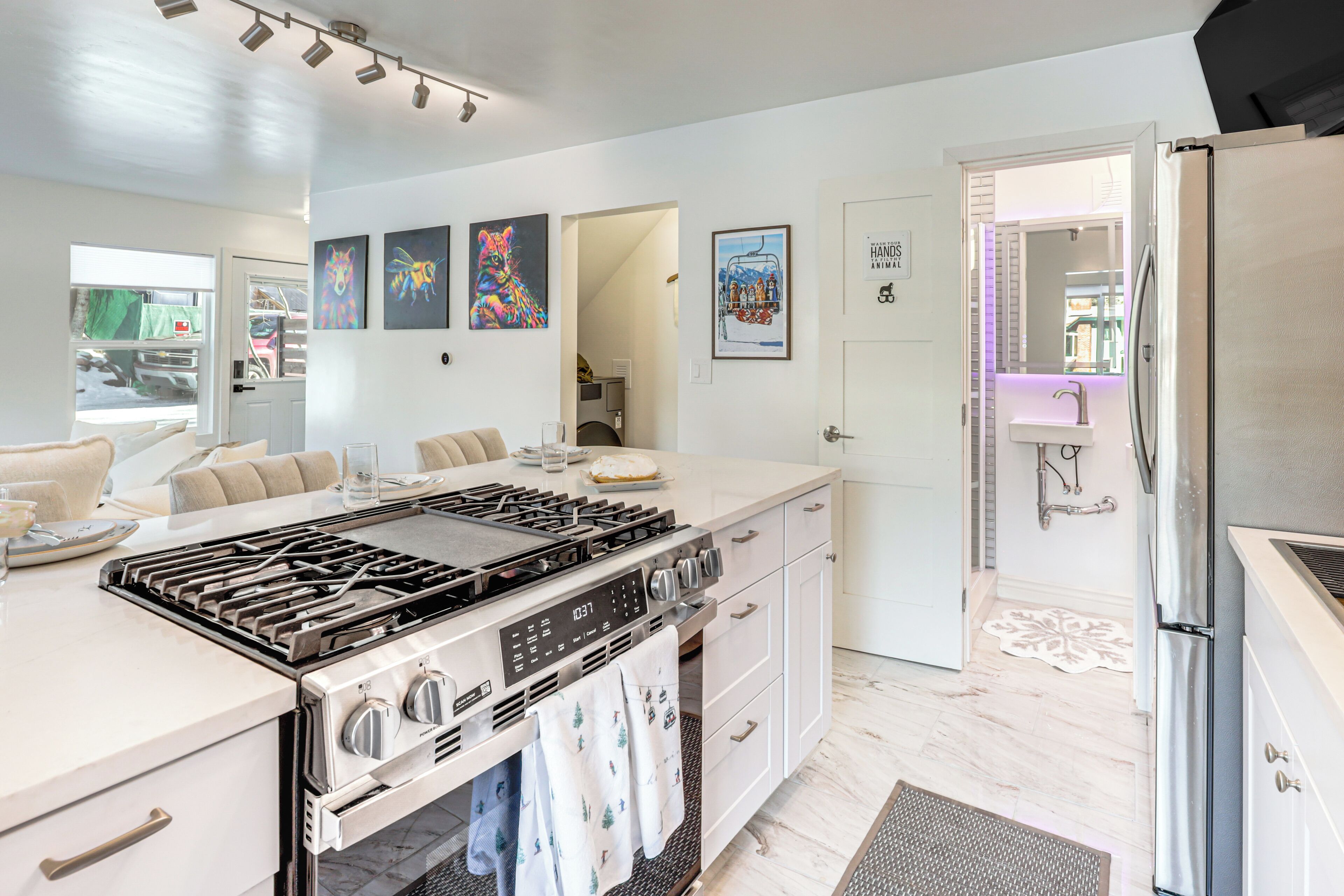A modern kitchen with a large island, stainless steel appliances, and artwork on the walls.