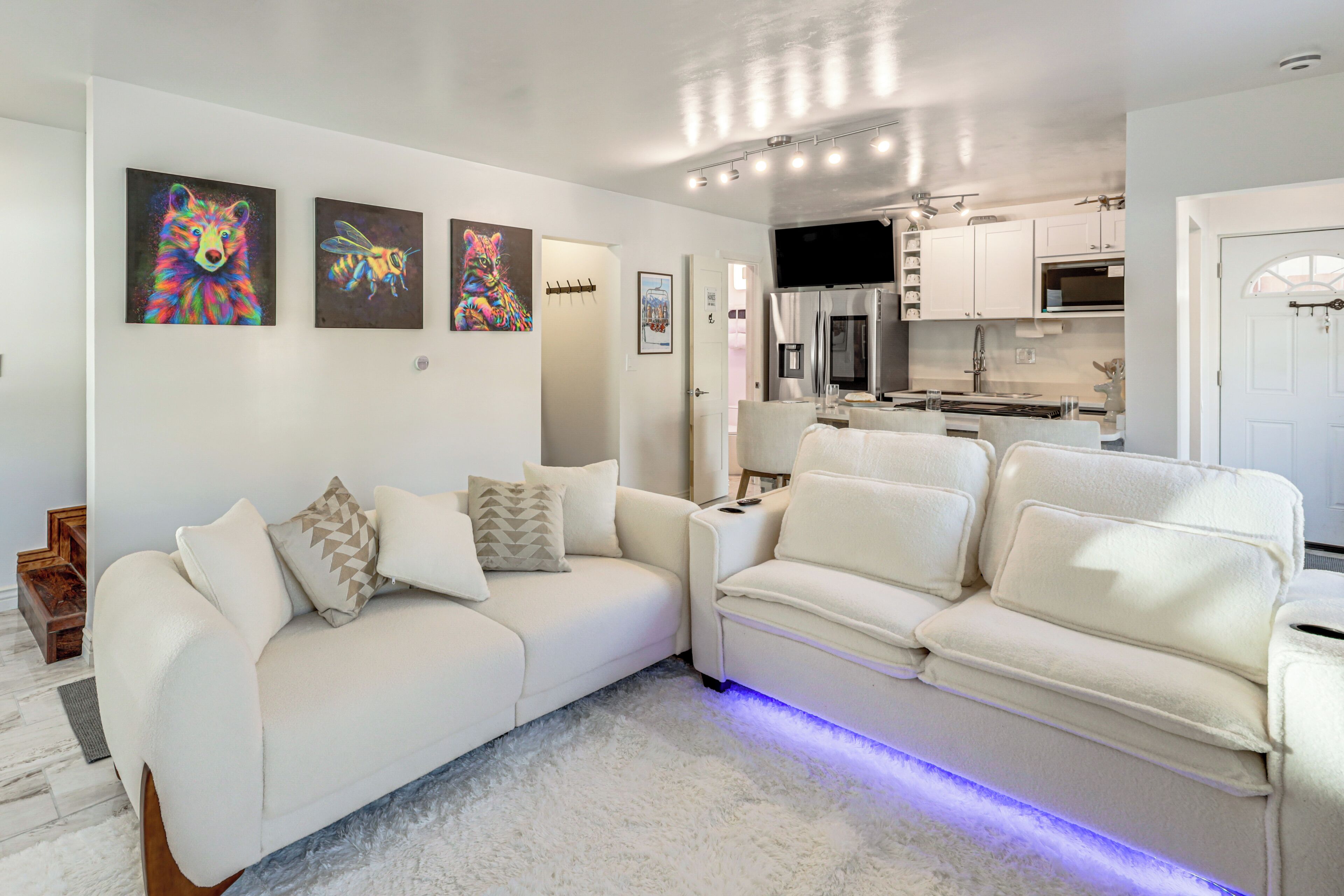 A modern living room with a white sofa, a flat-screen TV, and artwork on the wall.