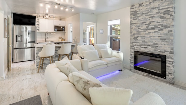 A modern living room with a white sofa, a fireplace, and a kitchen area in the background. - Newly Renovated, Modern Mtn Getaway: Pets Welcome! (Vail)