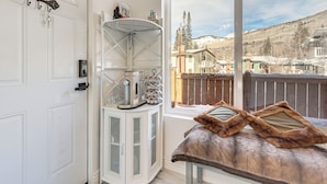 A room with a white cabinet, a window with a view of a snowy landscape, and a bench with fur throw pillows. - Newly Renovated, Modern Mtn Getaway: Pets Welcome! (Vail)