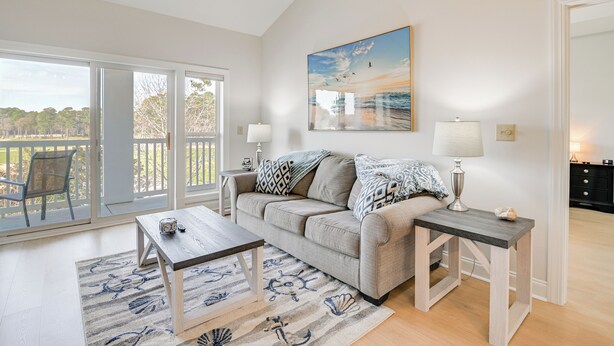 A spacious living room with a large window, a sofa, a coffee table, and a painting on the wall. - Golfers Paradise w/ Pool! 6 Mi to Myrtle Beach (Myrtle Beach)