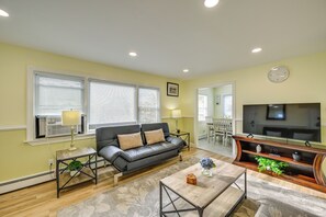A living room with a sofa, coffee table, TV, and a dining area in the background. - 6 Mi to Lower Manhattan: Apt w/ Shared Patio! (Jersey City)