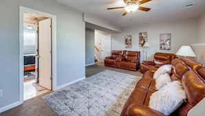 A spacious living room with a brown leather sofa, a patterned rug, and a ceiling fan. - 6 Mi to Downtown Birmingham! Family Home (Birmingham)