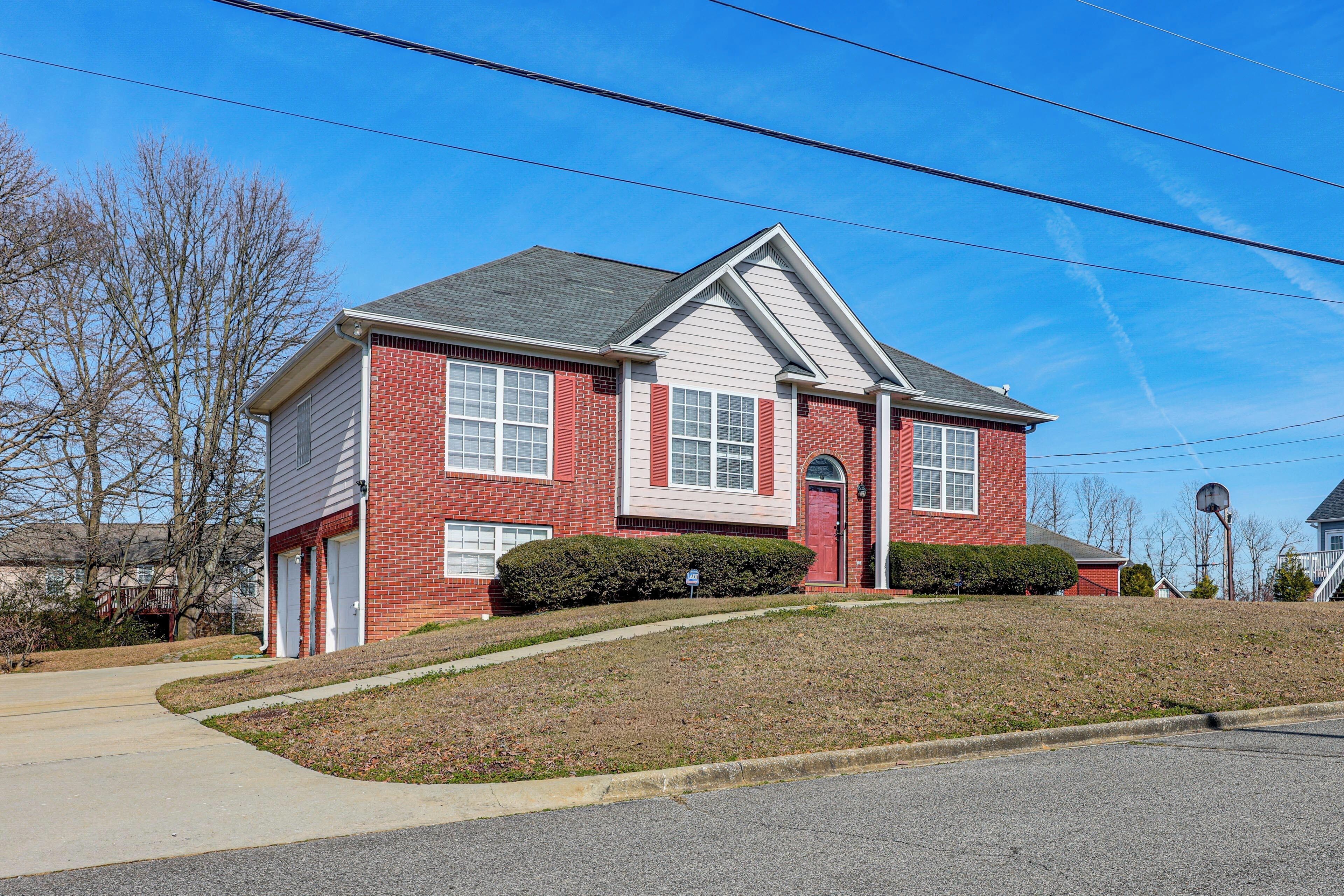A two-story house with a red brick facade, white trim, and a grey roof.
