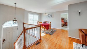 A spacious living area with hardwood flooring, a dining table with chairs, a staircase with white railings, and a red tablecloth. - 6 Mi to Downtown Birmingham! Family Home (Birmingham)