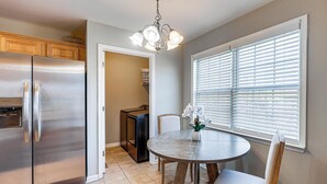 A kitchen with a stainless steel refrigerator, a dining table with chairs, and a window with blinds. - 6 Mi to Downtown Birmingham! Family Home (Birmingham)
