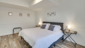 Ein ordentlich eingerichtetes Schlafzimmer mit einem großen Bett, Nachttischen mit Lampen und einem kleinen Beistelltisch.