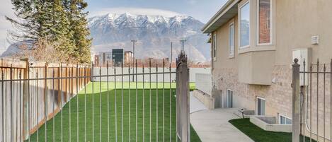 Una propiedad residencial con patio cercado, un sendero y montañas al fondo.