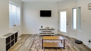 Ein modernes Wohnzimmer mit Flachbildfernseher, Couchtisch aus Holz und integrierten Regalen.