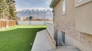 Ein Wohnhaus mit gepflegtem Rasen, Holzzaun und Blick auf die Berge.