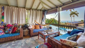 A cozy room with a hammock, wicker furniture, and a view of the ocean. - Lush Outdoor Space & Epic Views! Kailua-kona Home (Kailua-Kona)