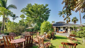 An outdoor seating area with wooden furniture and a covered patio. - Lush Outdoor Space & Epic Views! Kailua-kona Home (Kailua-Kona)