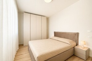 A bedroom with a bed, nightstand, and wardrobe. - Aurora Sand 1 - Carraro Immobiliare Jesolo (Jesolo)