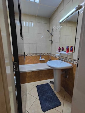 A bathroom with a bathtub, a sink, a shower, and a mirror. - Delightful 3-Bedroom Family Apartment with Garden View opposite to Safiya Garden (Sharjah)