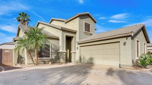A single-story house with a garage, a palm tree, and a clear blue sky. - Heated Pool, Pets Welcome: Surprise Snowbird Haven (Surprise)