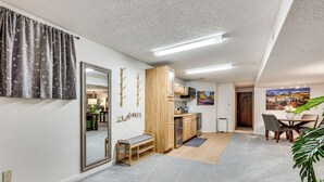 En rummelig opholdsstue med et køkken, spisebord og bænk.