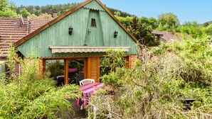 A rustic barn-style building with a green roof, wooden door, and a table with chairs outside. - Gîte Baumann Rombach le Franc – Cozy House with Terrace (Rombach le Franc)