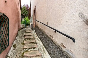 Eine enge Steinstufen-Treppe mit Metallgeländer, gesäumt von Gebäuden mit rosafarbenen und weißen Wänden.