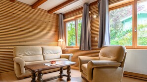 A room with a wooden slatted ceiling, a beige sofa, a wooden coffee table, and a beige armchair. - Gîte Baumann Rombach le Franc – Cozy House with Terrace (Rombach le Franc)
