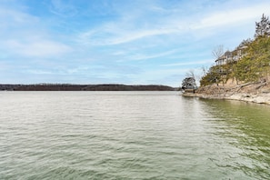A lake with a building on the right bank. - Private Dock at Ozarks Home Next to Margaritaville (Osage Beach)