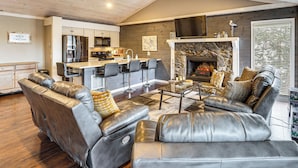 A modern living room with leather sofas, a kitchen area, and a fireplace. - Private Dock at Ozarks Home Next to Margaritaville (Osage Beach)