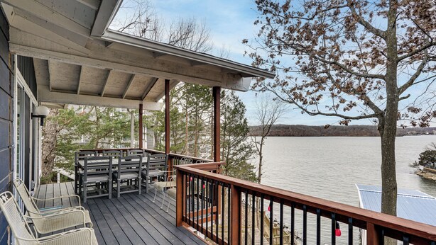 A wooden deck with outdoor furniture, overlooking a body of water and a distant landscape. - Private Dock at Ozarks Home Next to Margaritaville (Osage Beach)