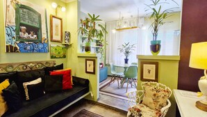 Un salon chaleureux avec un canapé aux couleurs sombres, une table à manger entourée de chaises et divers tableaux encadrés accrochés aux murs.