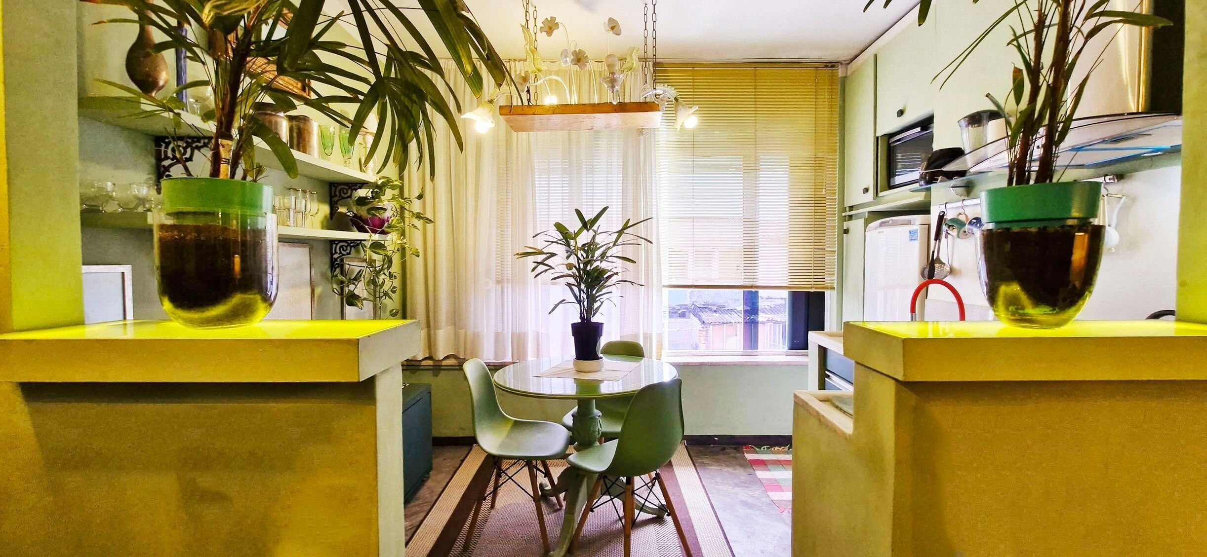 Uma cozinha compacta com uma mesa de jantar e cadeiras, cercada por plantas em vasos.