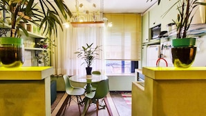 Une cuisine de taille réduite, avec une table et des chaises, entourée de plantes en pot.