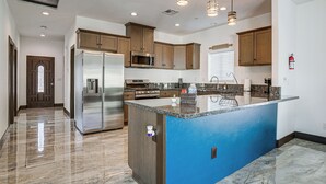 A modern kitchen with a central island, stainless steel appliances, wooden cabinets, and pendant lighting. - Fully Updated! Prime Riverside Spot Near Dtwn (Riverside)